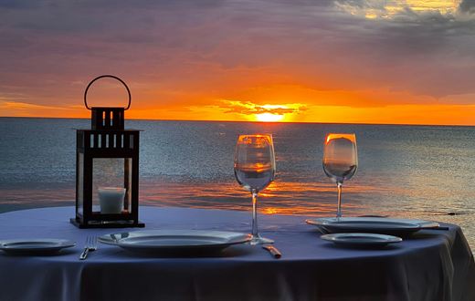 Private dinner table set with wine glasses and a lantern at dusk